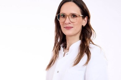 Hautärztin Dr. med. Schaaf trägt Brille und weißen Kittel und blickt sympathisch in die Kamera
