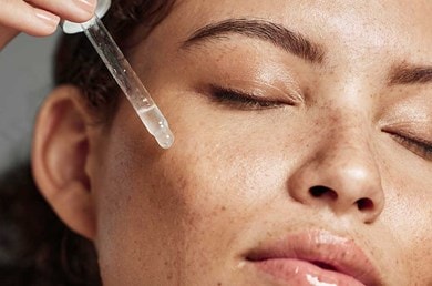 Nahaufnahme zeigt Anwendung eines flüssigen Serums auf der Wange