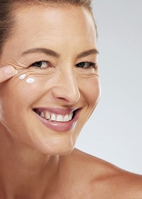 Frau trägt Anti-Aging-Serum auf fettige Haut auf, Nahaufnahme des Gesichts.