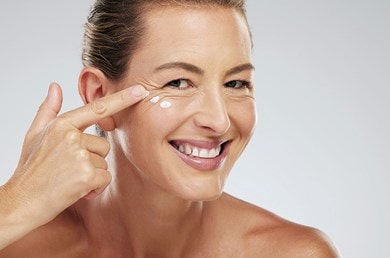 Frau trägt Anti-Aging-Serum auf fettige Haut auf, Nahaufnahme des Gesichts.