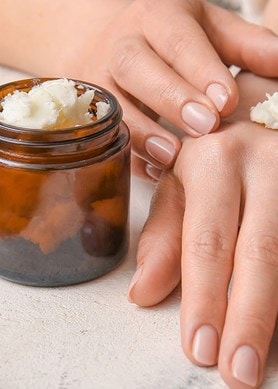 Nahaufnahme von Händen, die Pflegecreme mit Sheabutter auftragen – natürliche Feuchtigkeitspflege für trockene Haut